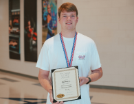  a male student holds an award certificate for being student of the month